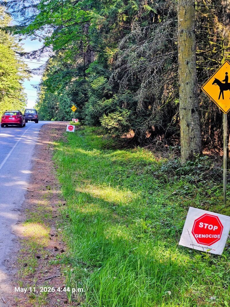 Four Stop Genocide signs in a row on North Road, Gabriola
