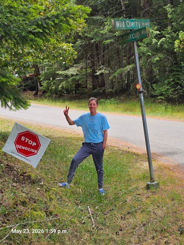 Cathy with her Stop Genocide sign at Wild Cherry Terrace, Gabriola