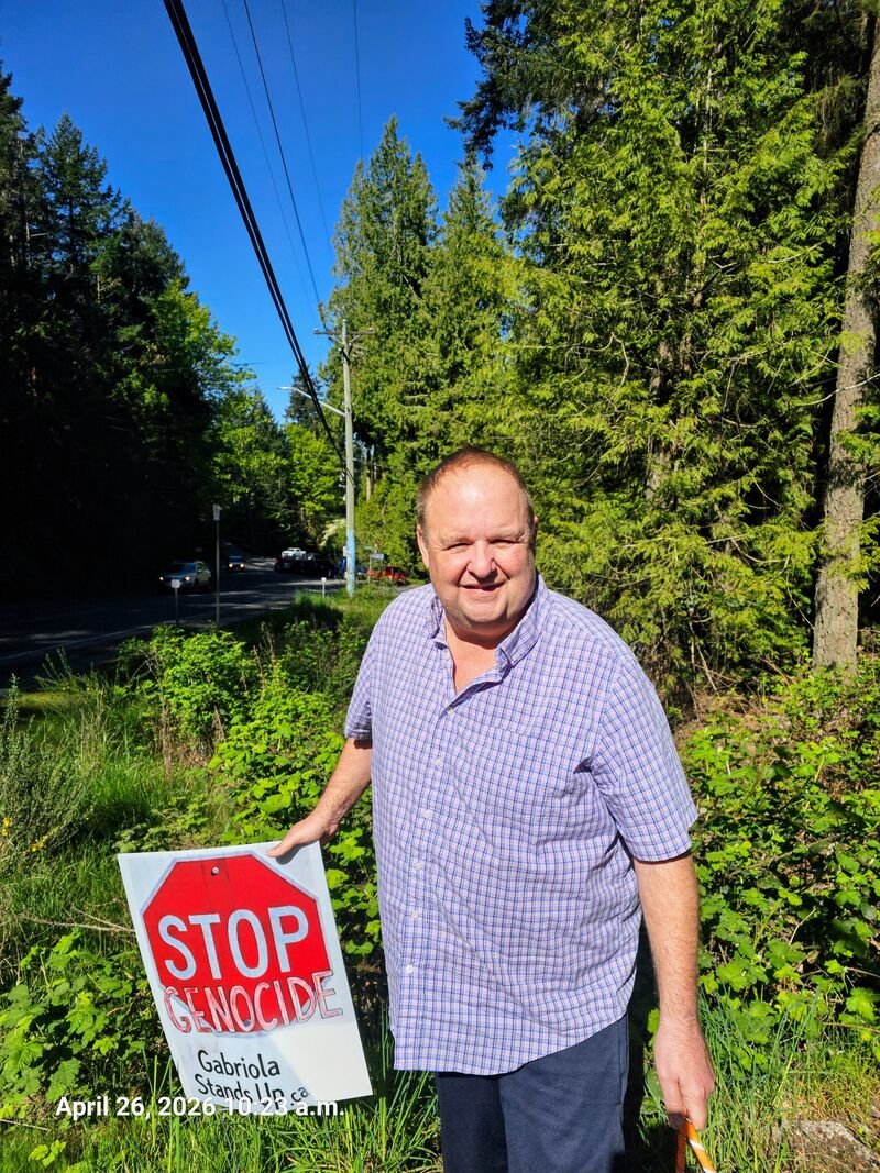 Russel with his Stop Genocide sign at the corner of North Road and Taylor Bay Road, Gabriola